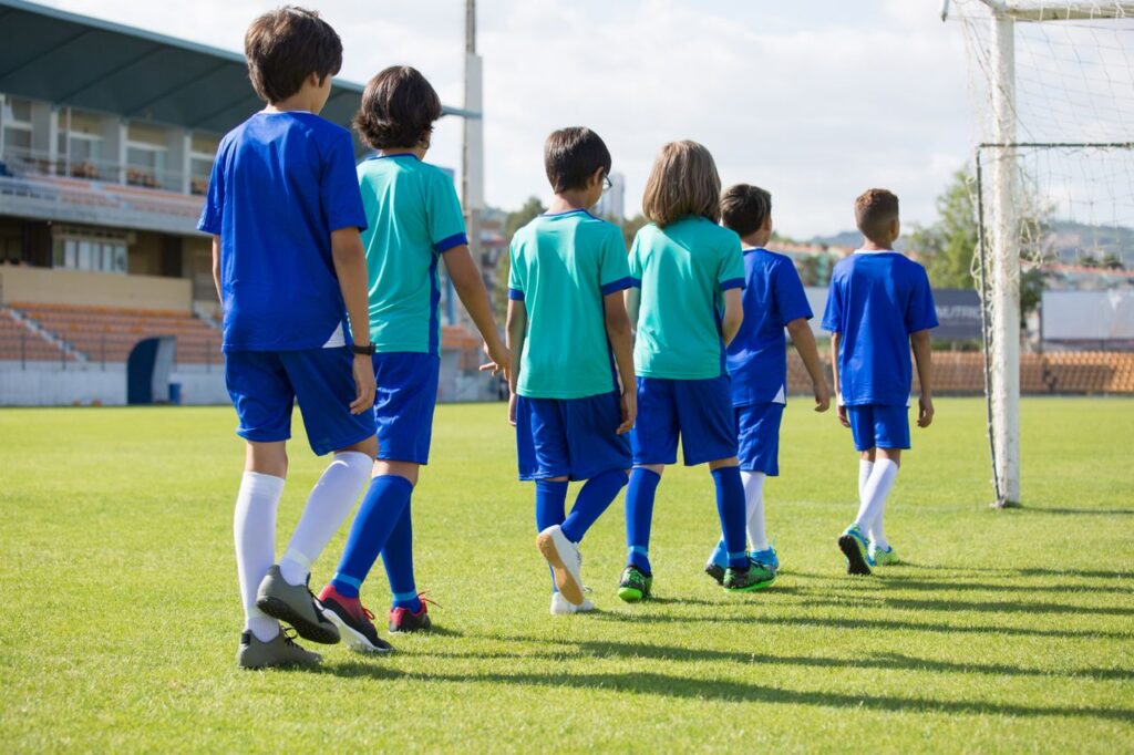 Youth soccer players in blue and teal uniforms standing together on the field